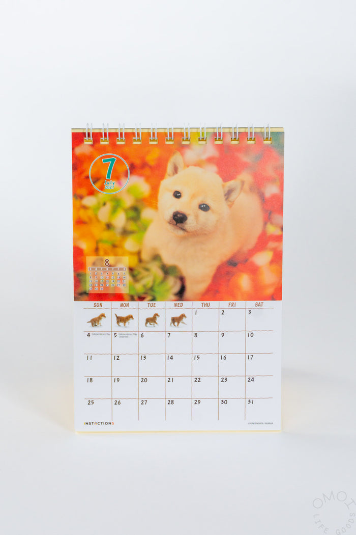 Desk calendar with Shiba Inu puppy cover, spiral rings, monthly grid.