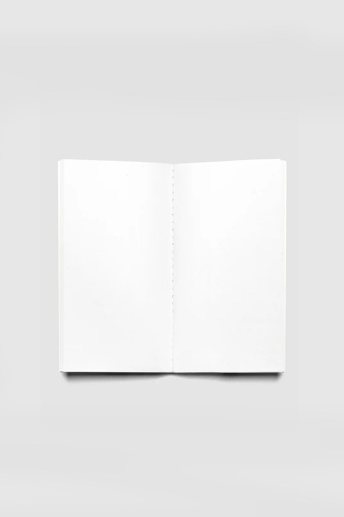 Blank travel notebook opened flat, white pages with stitched binding