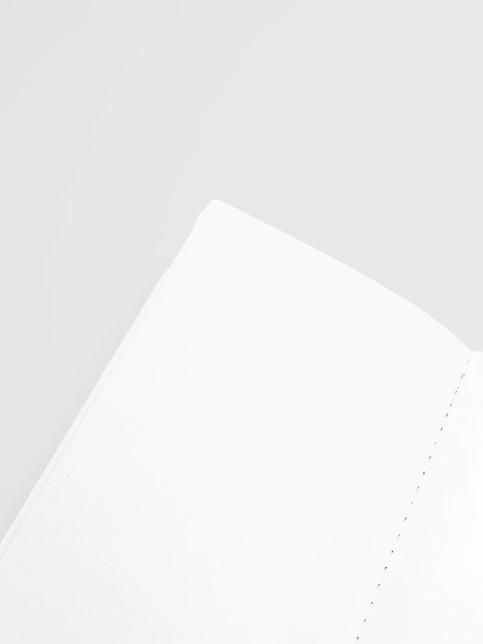 Close-up of blank notebook page corner with dotted stitching