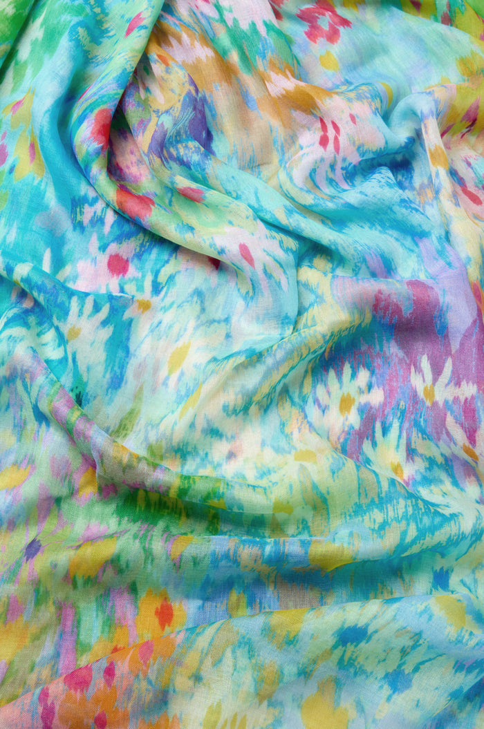 Close-up of the Dreamy Floral Oasis Scarf, featuring a colorful abstract pattern in blue, green, yellow, pink, and orange hues on a modal silk blend—lightweight and softly draped with slight wrinkles, perfect as a stylish scarf.