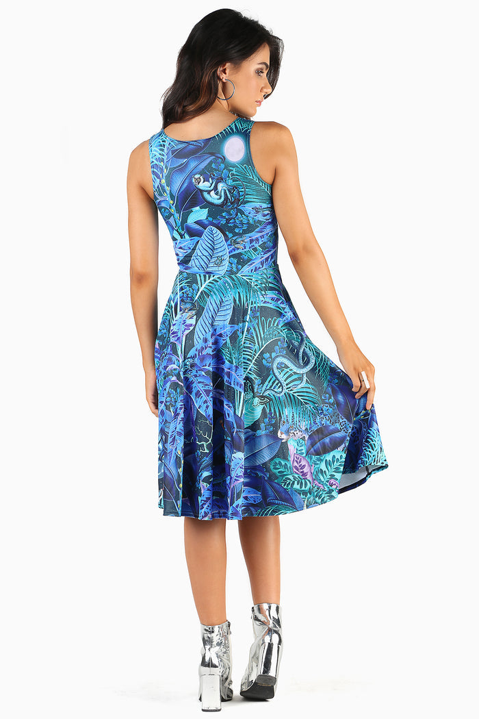 Woman wearing a dress with a blue and green jungle print featuring birds and foliage on a white background