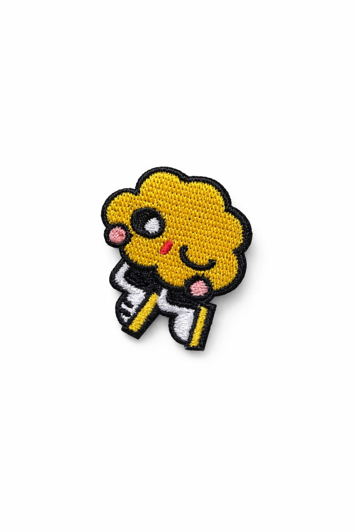 Small embroidered pin featuring a yellow skater character with black outline and smile