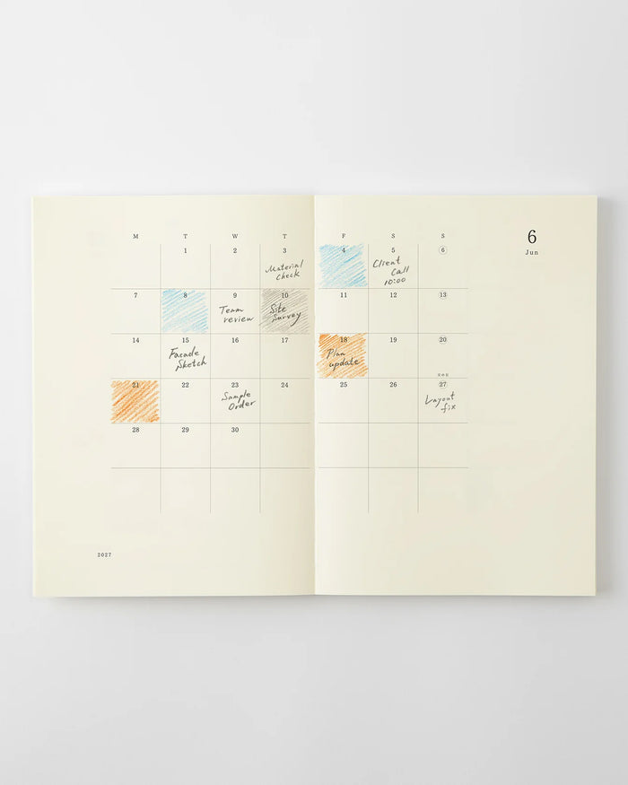 MD notebook monthly calendar spread with handwritten notes and colored date marks