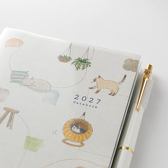 Close-up of 2027 cat-illustrated planner cover with pen and gold accents.