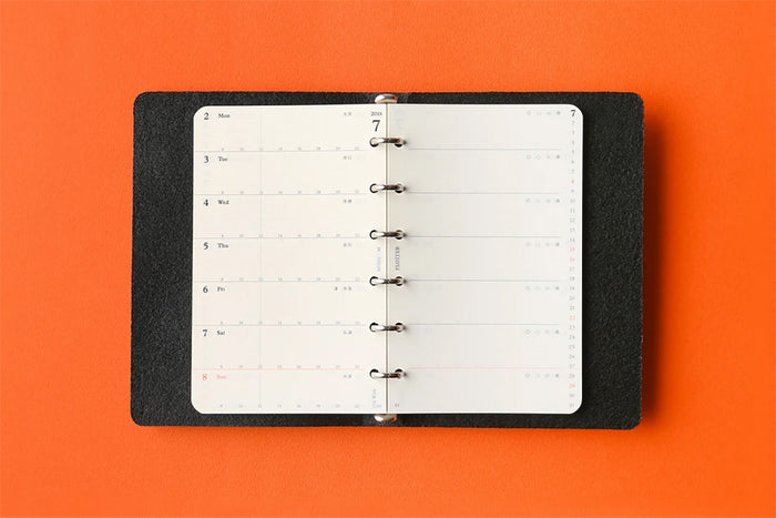 Weekly schedule refill opened in a binder, showing day rows across the page