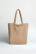 The Soft Suede Sand Tote Bag in beige features a spacious interior, two handles, and a front bow detail, shown against a plain light background.