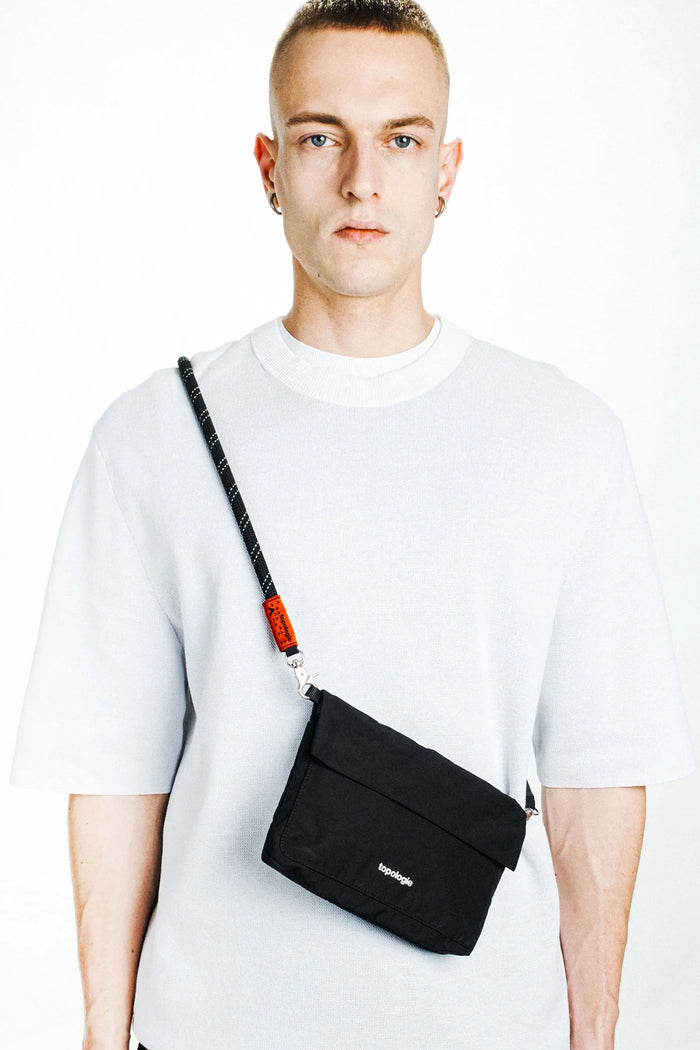 Black rope strap on small crossbody bag, worn over the shoulder