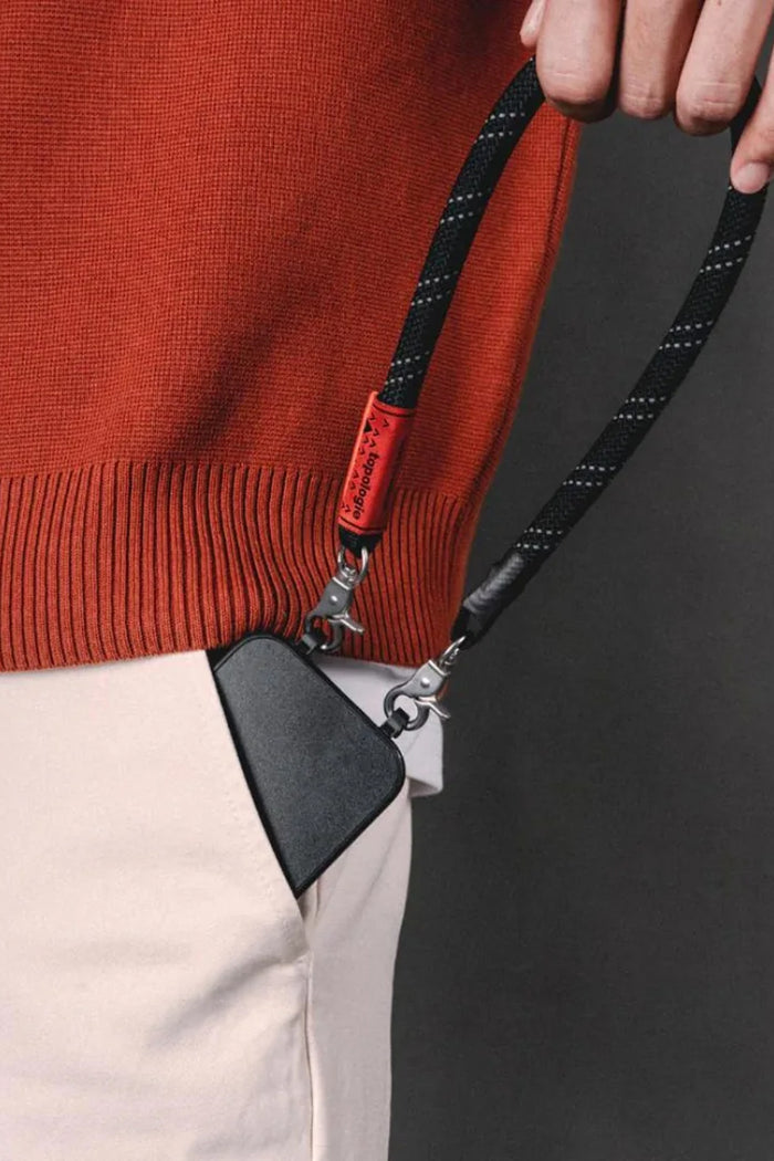 Black and red reflective wrist strap with clips holding a small pouch