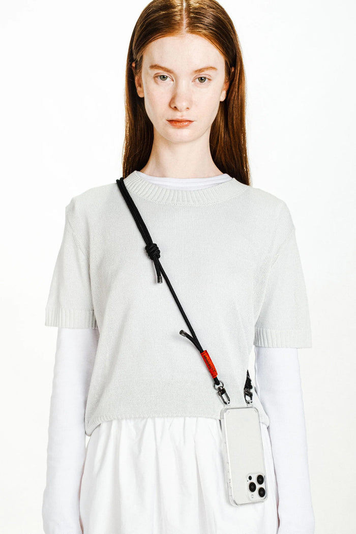 Black rope strap with red accent and clear phone case, worn crossbody
