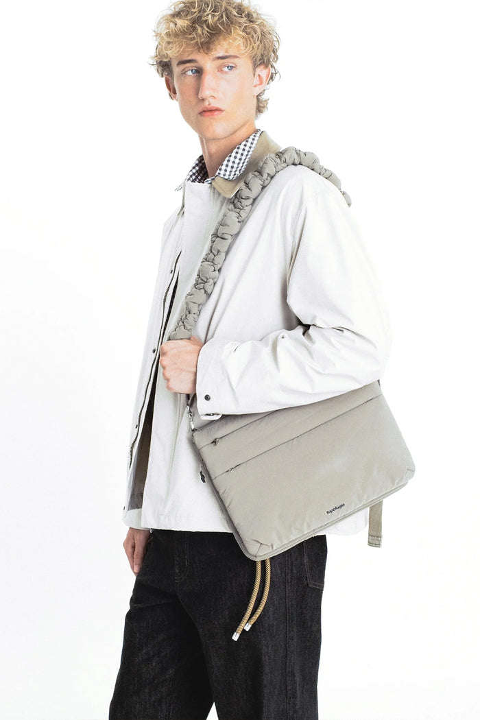 Braided light-gray crossbody strap with metal clips on a jacket