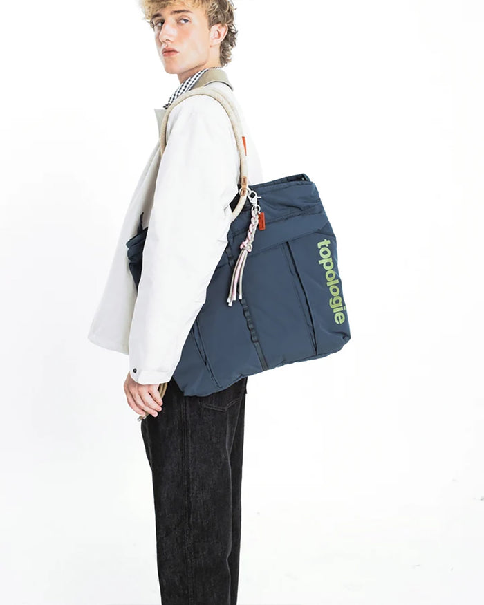 Topologie Sinnet keychain with braided tassels and metal clip on blue bag strap